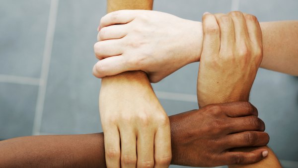 Nahaufnahme von 4 Menschen, die sich am Handgelenk anfassen