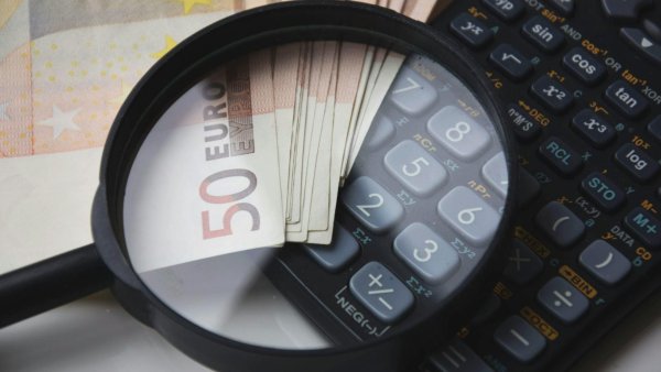 Geld und Taschenrechner liegen unter der Lupe
